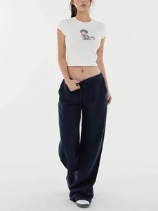 Detail of navy blue wide-leg trousers and white crop top with cat graphic print