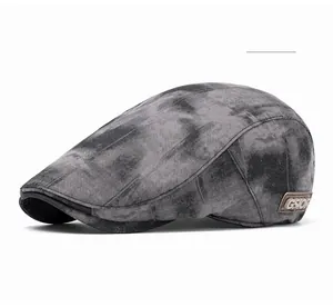 Close-up of retro tie-dye flat cap featuring a brown leather label and metal logo detail
