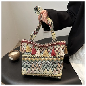 Detailed close-up of a large bohemian woven tote bag with colorful tassels and wave patterns