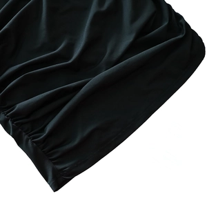 Close-up view showing the textured black fabric and refined hem finish of the dress