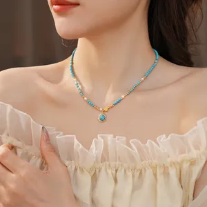 Collier plaqué or avec cœur, pendentif turquoise et perles sur un mannequin femme