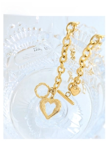 Detail of 18k gold heart pendant with wing texture and OT toggle clasp on glass