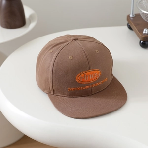 Detailed close-up of orange embroidery text on a dark brown snapback hip-hop cap