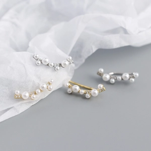 Detailed view of pearl earrings with zircons in gold and silver finish on textured paper