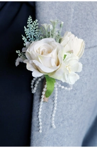 Detail of white artificial rose boutonniere with elegant pearl fringe and twine wrap