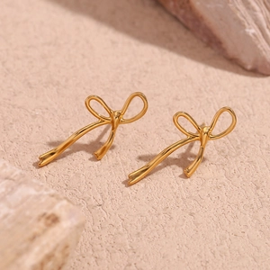 Macro shot of 18K gold plated stainless steel bow earrings on a textured stone base