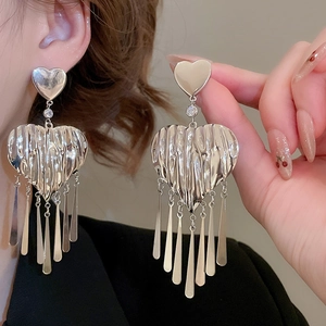 Detailed close-up of silver heart-shaped tassel earrings featuring unique wrinkled metal texture