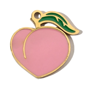 Macro detail of peach-shaped enamel charm with pink finish and gold-plated edges