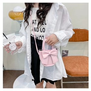 Detailed view of a pink leather bucket bag with a bow decoration in a cafe setting