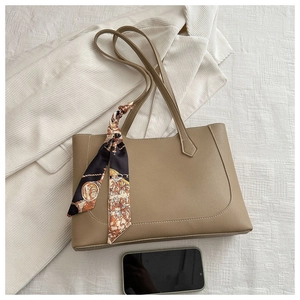 Détail d'un sac cabas en cuir kaki avec un foulard en soie vintage imprimé sur l'anse