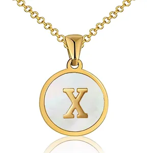 Detailed macro shot of a gold round pendant necklace featuring letter X and mother of pearl
