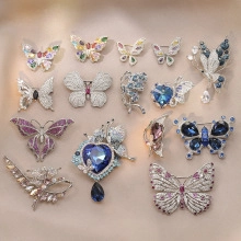 Flat lay of diverse butterfly and flower brooches with colorful rhinestones on fabric