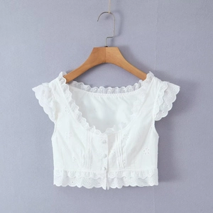 Gros plan sur les détails de broderie en dentelle blanche d'un crop top boutonné