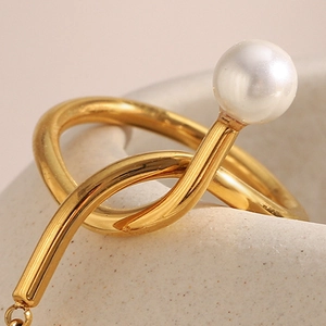 Gros plan sur une bague nouée dorée avec perle blanche sur une surface en céramique