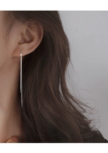 Close-up of minimalist long silver tassel linear earrings worn by a female model