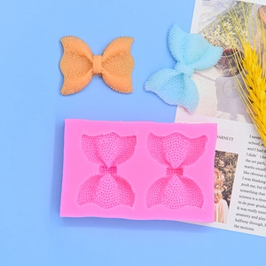 Pink silicone bow-shaped fondant mold with two cavities and textured finish detail