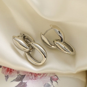 Modern silver geometric chain link earrings displayed on elegant beige silk fabric