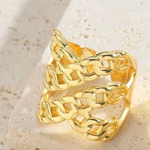 Close-up of a gold triple-layer chain ring on a textured beige stone pedestal