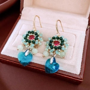 Macro detail of ethnic glass beaded flower earrings with a blue heart crystal drop