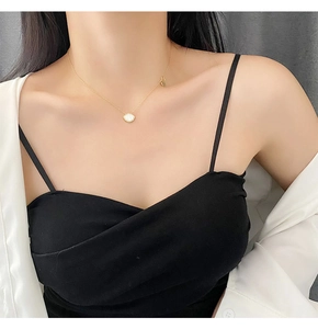 Close-up of golden titanium necklace with white shell pendant on woman's collarbone
