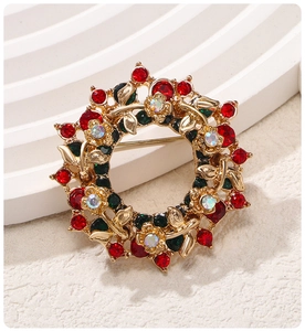Close-up of golden wreath brooch with vibrant red and rainbow crystals on a textured surface