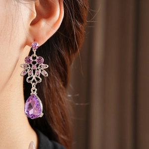 Macro shot of silver vintage earrings with purple teardrop crystals on model