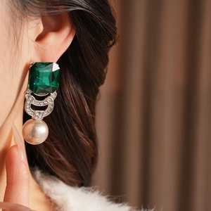 Dettaglio di orecchini vintage con gemma verde taglio smeraldo e perle eleganti