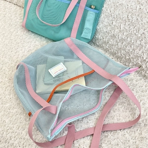 Close-up of mesh beach bag with pink strap and orange interior pocket detail
