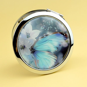 Portable silver metal compact mirror with a vibrant blue butterfly and white floral design