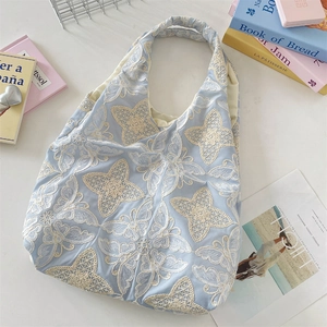 Gros plan d'un sac cabas bleu clair avec broderie détaillée en dentelle papillon