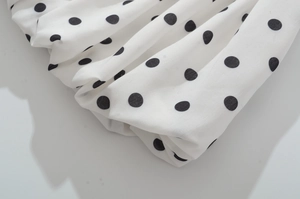 Détail du tissu blanc à pois noirs avec des plis naturels et une texture délicate