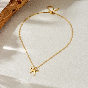 Elegante collana dorata con ciondolo a fiocco e catena a sfere su fondo materico