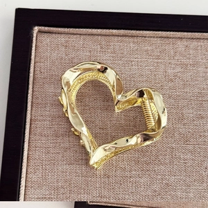 Macro shot of a golden heart-shaped metal hair claw clip with twisted streamlined design