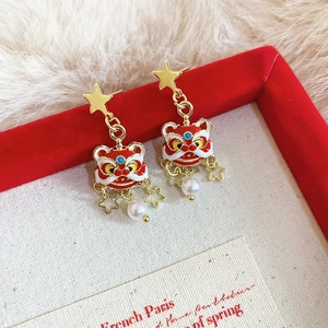 Vue détaillée des boucles d'oreilles lion de danse en émail rouge avec perles