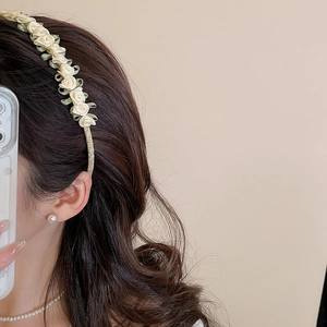 Detail of floral headband featuring soft yellow ribbon roses and model wearing pearl earrings