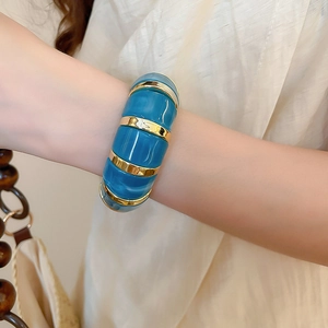 Detail of wide resin and gold metal segmented bracelet showing blue marble texture