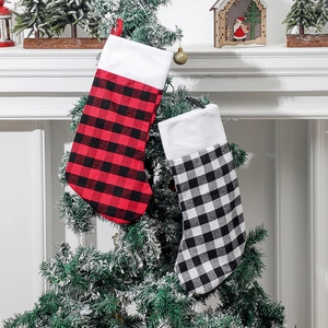 Classic red black and white plaid Christmas stockings hanging on a snowy festive tree