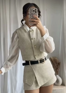 Detail of tweed vest and skirt set with pearl collar blouse and black belt