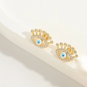 Close-up of golden evil eye stud earrings with blue enamel and sparkling zircon accents