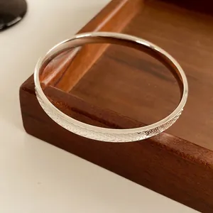 Minimalist silver round cuff bracelet with luxury honeycomb scale texture on dark wood tray