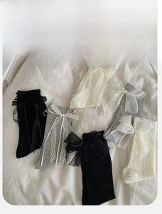 Detailed view of Lolita style mid-calf socks with lace trim and mesh bow accents