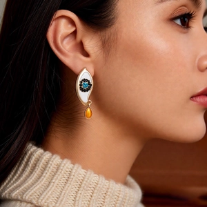 Detail view of eye-shaped vintage earring with blue stone and orange teardrop crystal