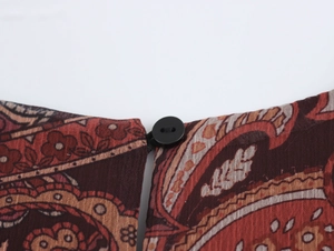 Détail de l'encolure ronde avec bouton sur la robe longue en mousseline à motif paisley