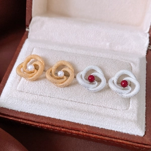Close-up of vintage knot earrings with pearl and red bead in a jewelry box