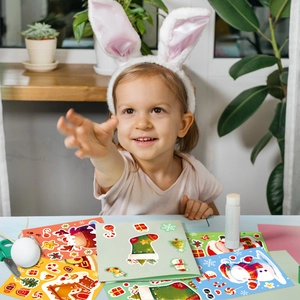 Little girl playing with festive DIY Christmas stickers featuring Santa and reindeer designs