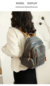 Vista trasera de una mochila gris de tela Oxford con costuras acolchadas y tachuelas