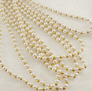 Gros plan de perles blanches et billes dorées sur fond en peluche blanche douce