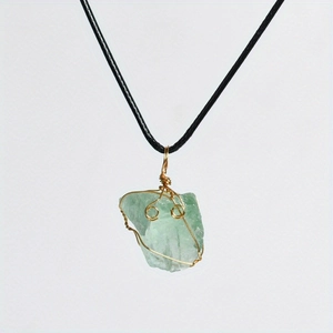 Detail of handcrafted green fluorite raw crystal pendant with gold wire wrapping