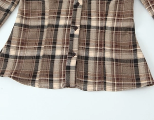 Vue détaillée de la texture du tissu de chemise à carreaux marron et des boutons
