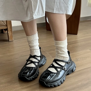 Dettaglio di scarpe Mary Jane nere con plateau e cinturini incrociati su pavimento